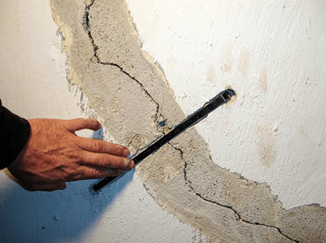 A wall with a large crack is being inspected by a professional in Colorado Springs, CO